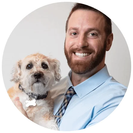 Joshua Broadwater smiling and holding a small terrier mix dog