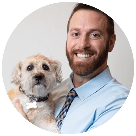 Joshua Broadwater smiling and holding a small terrier mix dog